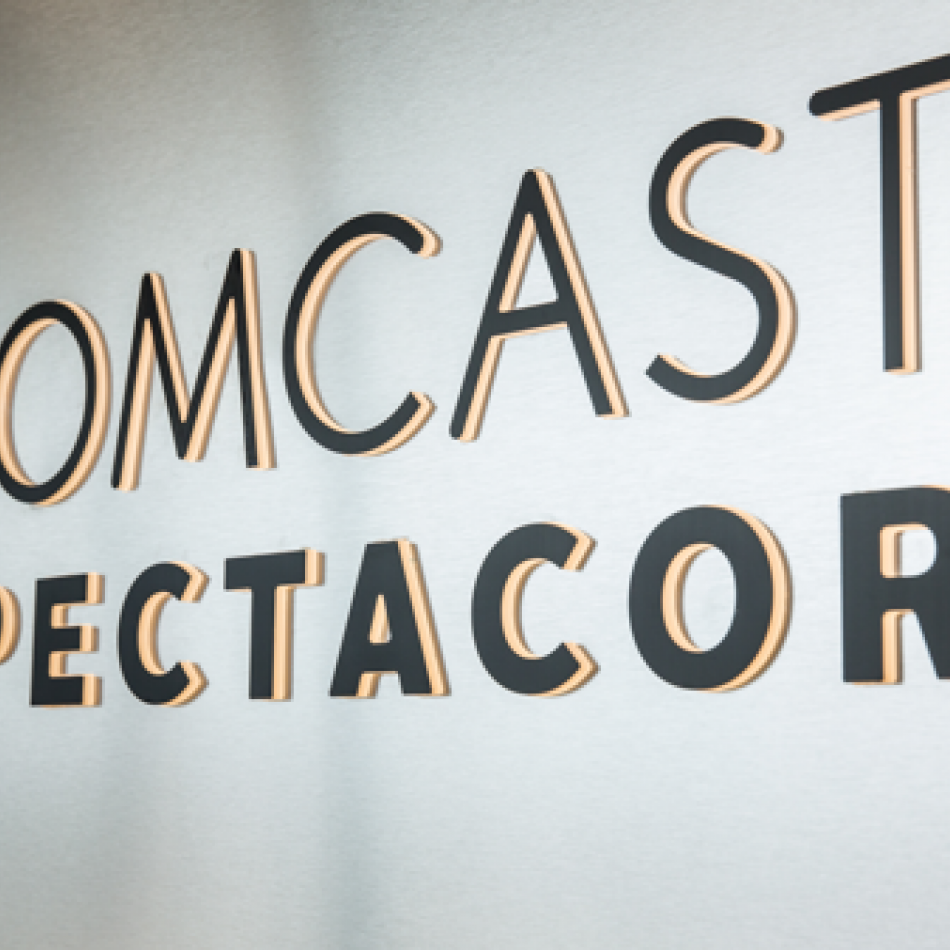 Signage of Comcast Spectacor logo in black on a silver background.